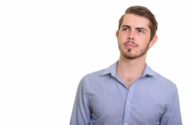 Portrait of young handsome bearded businessman thinking and looking up