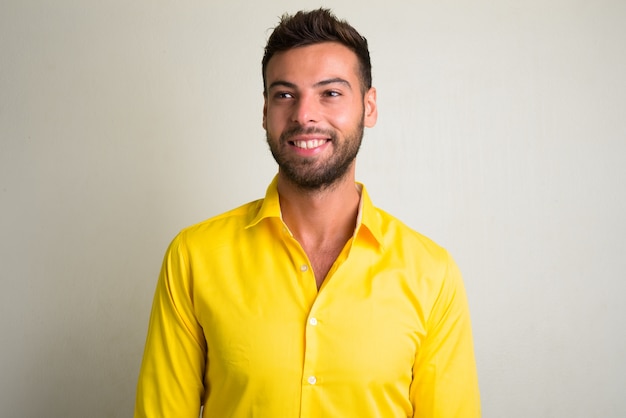 portrait of young handsome bearded businessman wearing yellow shirt on white