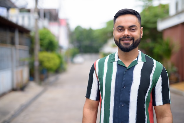 Photo portrait of young handsome bearded indian man in the streets outdoors