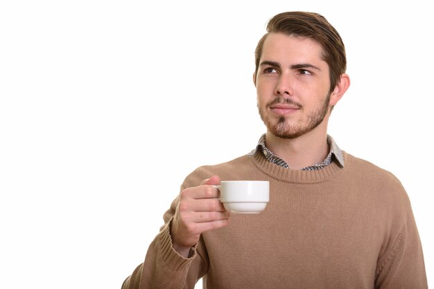 Portrait of young handsome bearded man drinking coffee