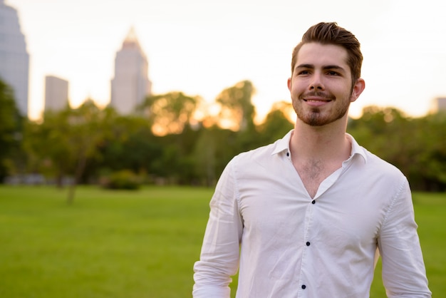 Portrait of young handsome bearded man relaxing at the park outdoors