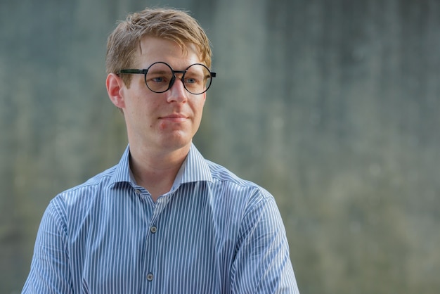 Portrait of young handsome blond businessman in the city streets outdoors