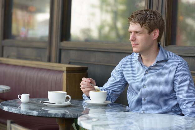 Portrait of young handsome blond businessman relaxing at the coffee shop outdoors