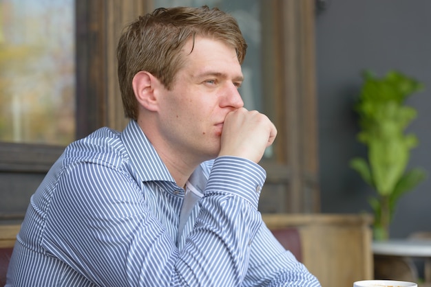 Portrait of young handsome blond businessman relaxing at the coffee shop outdoors