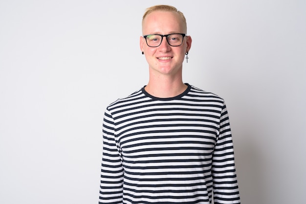 portrait of young handsome blonde hipster man looking cool with monochrome clothing on white