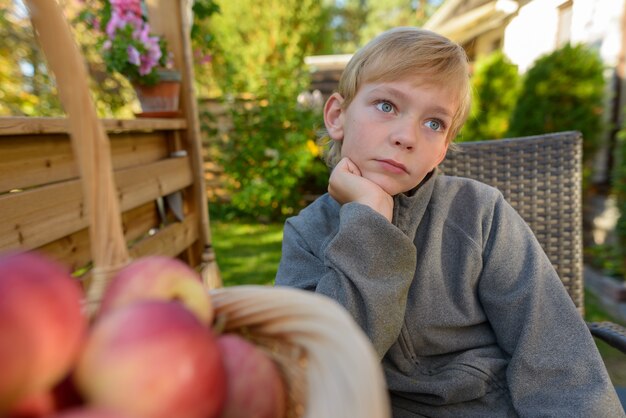 Portrait of young handsome boy with blond hair in the backyard garden at home