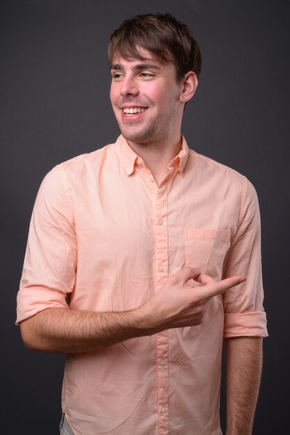 Portrait of young handsome businessman against gray wall