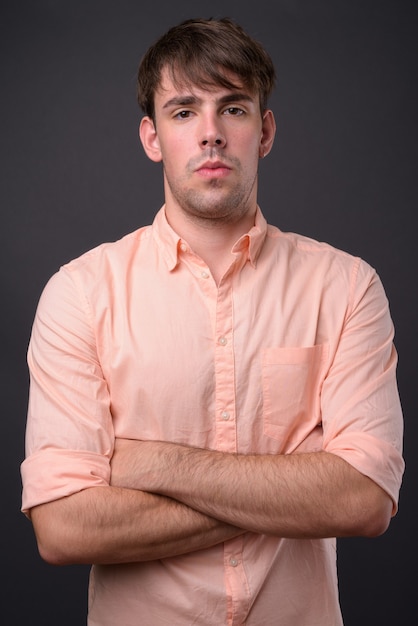 Portrait of young handsome businessman against gray wall