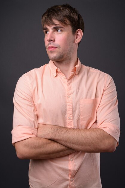 Portrait of young handsome businessman against gray wall