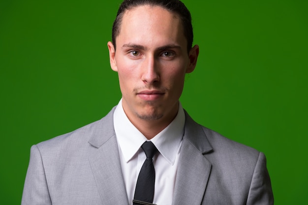 Photo portrait of young handsome businessman against green wall