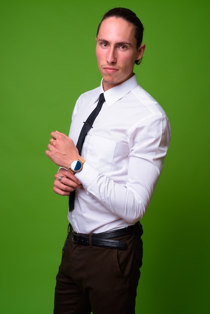 Portrait of young handsome businessman against green wall