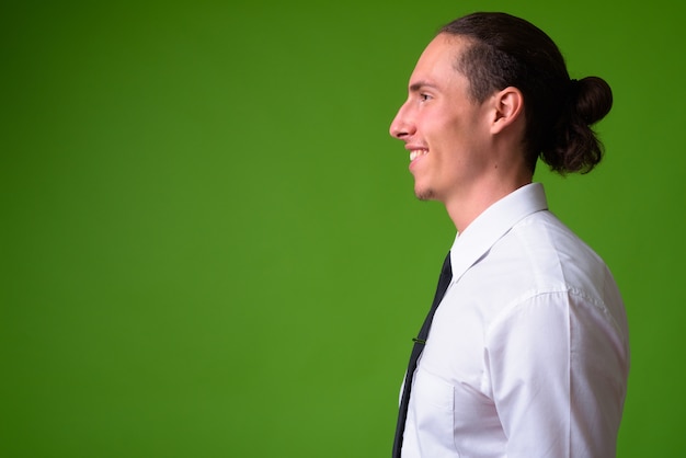 Portrait of young handsome businessman against green wall