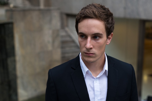 Portrait of young handsome businessman in the city outdoors