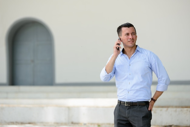 Portrait of young handsome businessman outside the building in the city