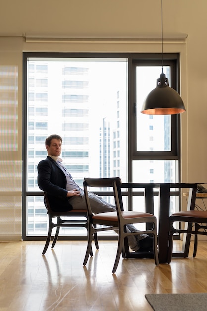 Portrait of young handsome businessman sitting in the dining room near the kitchen