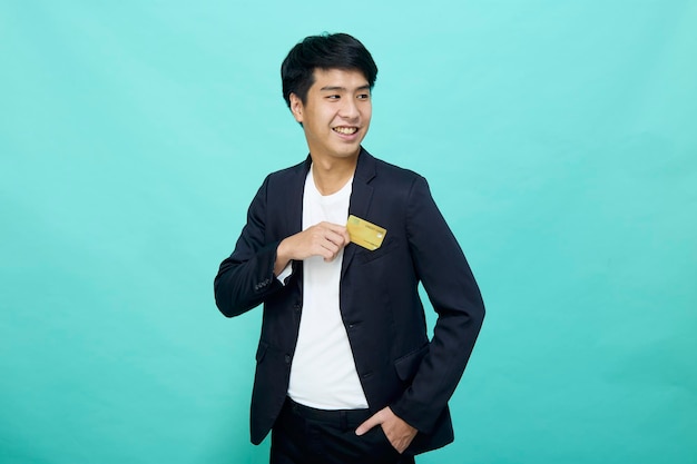 Portrait Young handsome businessman in a suit holding yellow credit card isolated in a blue studio