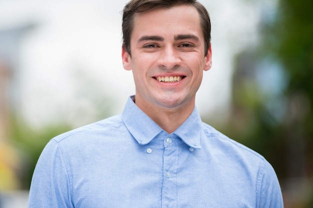 Portrait of young handsome businessman wearing smart casual clothing in the streets outdoors