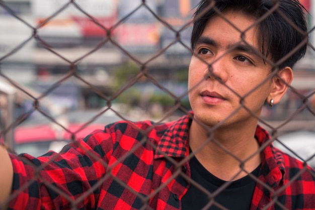 Portrait of young handsome Filipino hipster man in the city streets outdoors