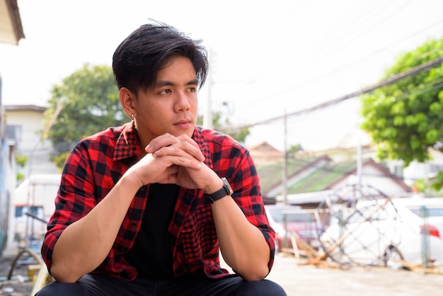 Portrait of young handsome Filipino hipster man in the streets outdoors