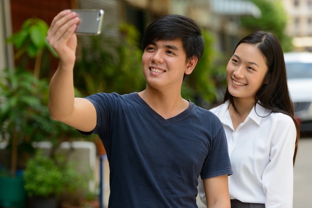 Portrait of young handsome Filipino man and young beautiful Asian woman together in the streets outdoors