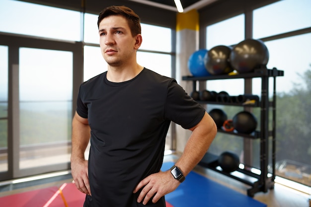 Portrait of a young handsome fitness trainer in a gym