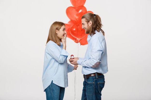 Portrait of Young handsome guy gives a ring to a girl 