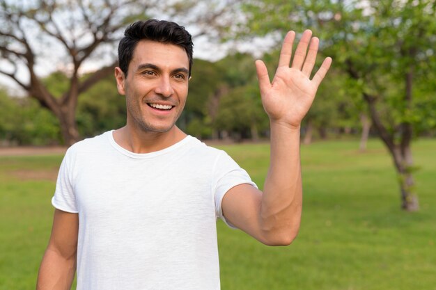 Portrait of young handsome Hispanic man in the park outdoors