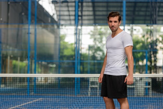 Portrait of young handsome Hispanic man ready to play at the padel court