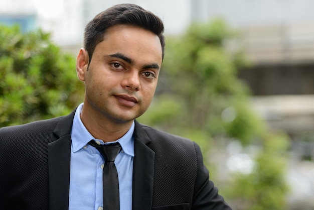 Portrait of young handsome Indian businessman in the city