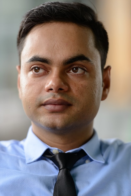 Portrait of young handsome Indian businessman in the city