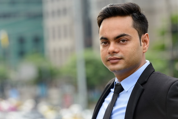 Portrait of young handsome Indian businessman in the city