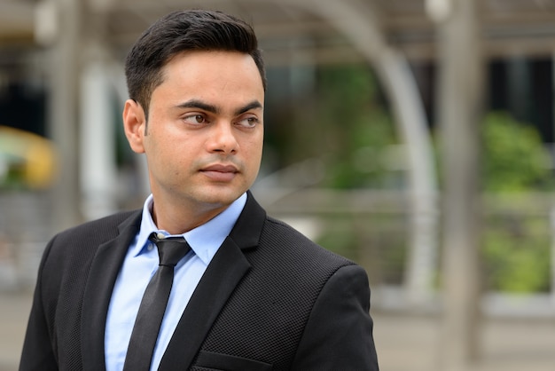 Portrait of young handsome Indian businessman in the city