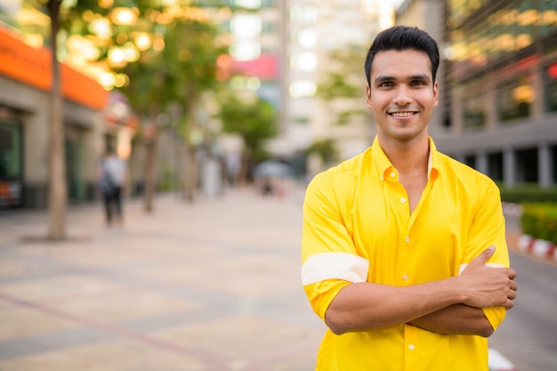 Portrait of young handsome Indian man in the city streets outdoors
