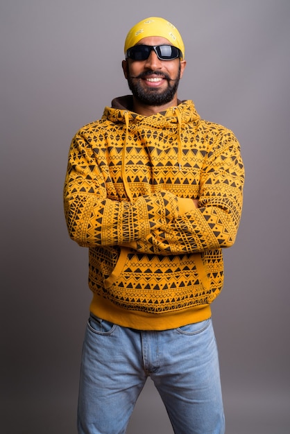 Portrait of young handsome Indian man wearing hoodie