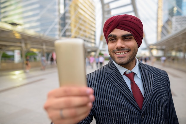 Ritratto di giovane uomo d'affari indiano bello sikh che indossa turbante mentre esplora la città di bangkok, thailandia