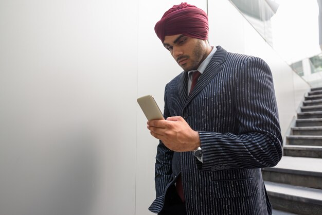 Portrait of young handsome Indian Sikh businessman wearing turban while exploring the city of Bangkok, Thailand