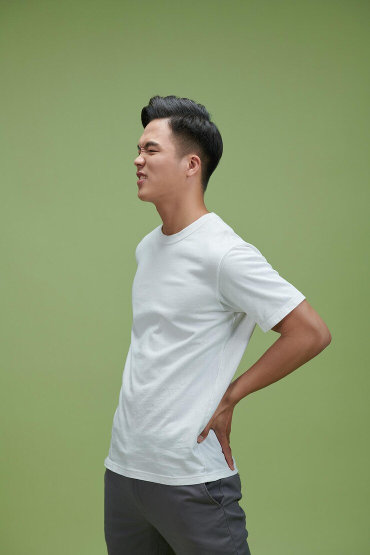 Photo 緑の背景に分離された腰痛を持つ若いハンサムな男性の肖像画