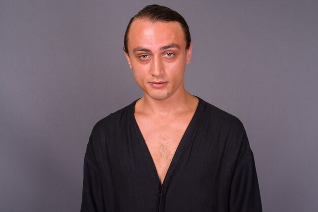 Portrait of young handsome man against gray wall