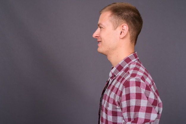 Portrait of young handsome man against gray wall