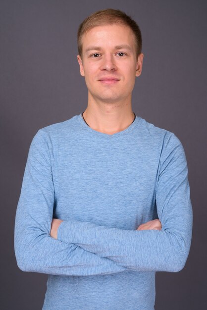 Portrait of young handsome man against gray wall