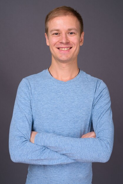 Portrait of young handsome man against gray wall