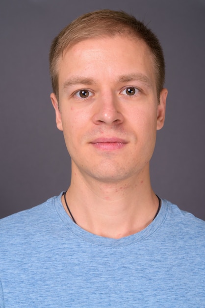 Portrait of young handsome man against gray wall