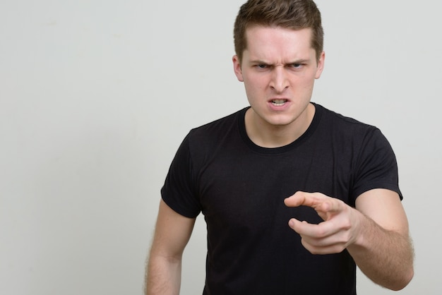 Portrait of young handsome man against white wall