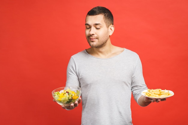 Portrait of young handsome man craving after junk food instead of eating healthy food