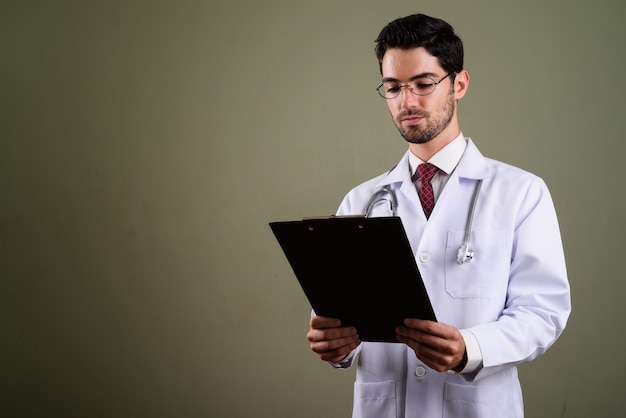 Portrait of young handsome man doctor with eyeglasses holding clipboard