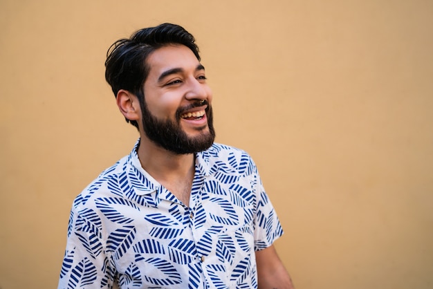 Portrait of young handsome man enjoying summer and wearing summer clothes against yellow background.