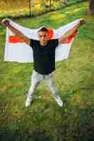 Photo portrait of young handsome man holding flag of england isolated over natural landscape top view