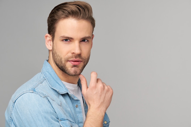 Photo portrait of young handsome man in jeans shirt over light wall