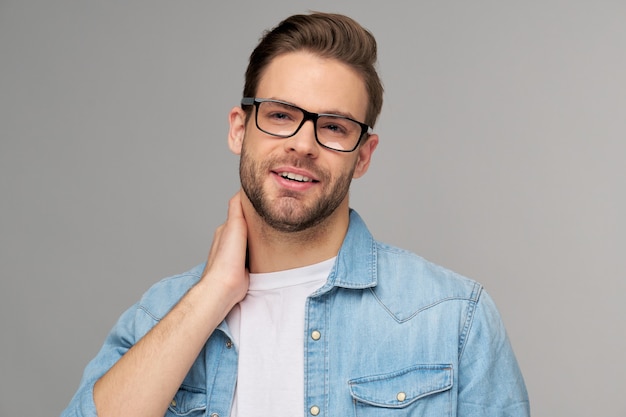 Portrait of young handsome man in jeans shirt over light wall