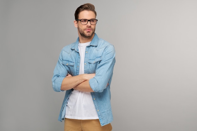 Portrait of young handsome man in jeans shirt over light wall